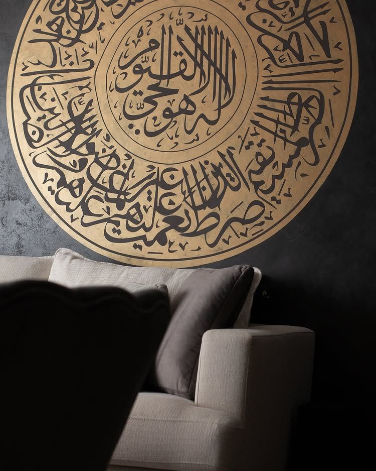 Dark textured wall with a large gold calligraphy medallion and a light sofa